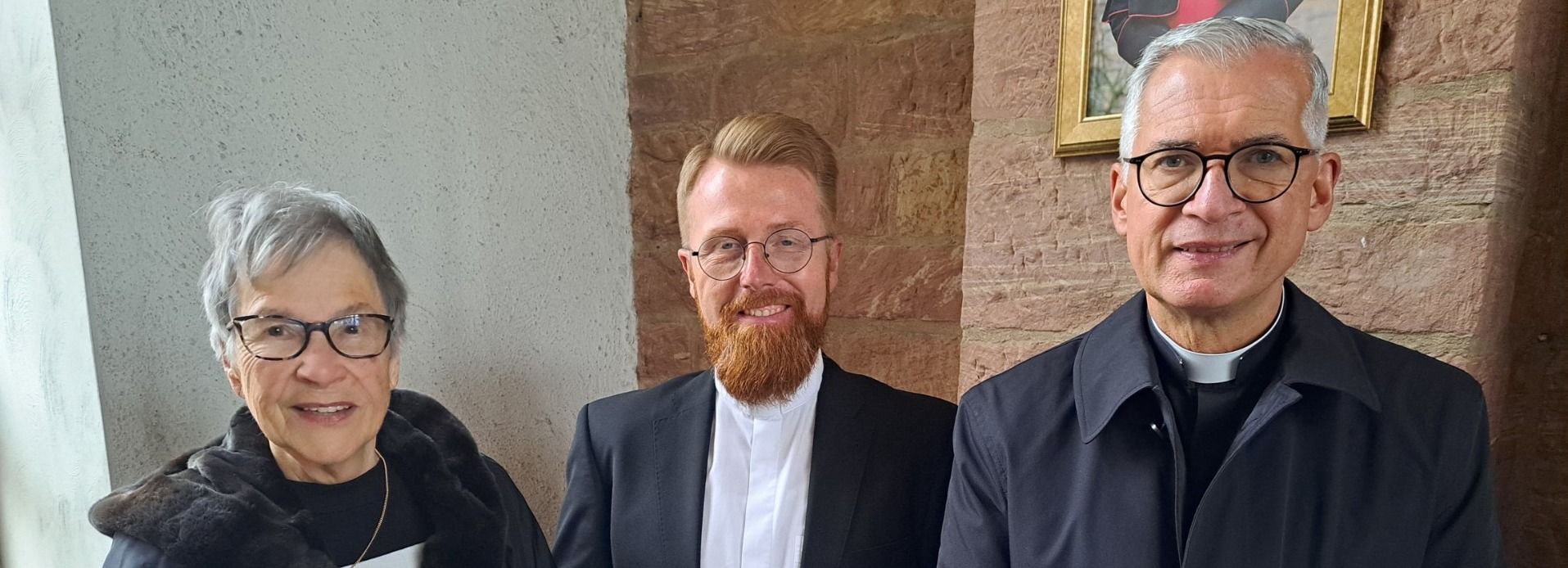 Gisela Hardegen (während der Brandnacht 9 Jahre alt) mit den Hanauer Pfarrern Manuel Stickel und Dirk Krenzer. Auf dem Tisch die historischen „Fluchtschuhe“ von Willi Oschwald (damals keine 6 Jahre alt).